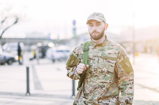 Junger Militärmann in einer Tarnuniform und in einer Kappenstellung