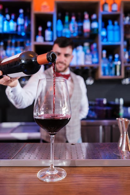 Junger Mixologe serviert seinem Kunden ein Glas Wein Konzeptgetränk Wein-Önologie