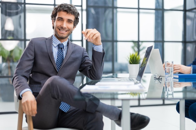 Junger moderner Geschäftsmann, der mit dem Computer arbeitet, während er im Büro sitzt