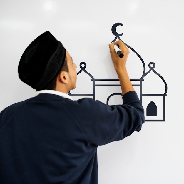 Junger moslemischer Mann, der eine Moschee auf einem whiteboard zeichnet