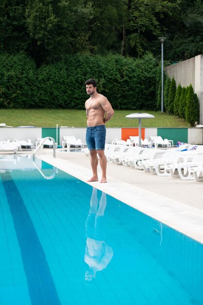 Junger muskulöser Mann am Swimmingpool im Freien