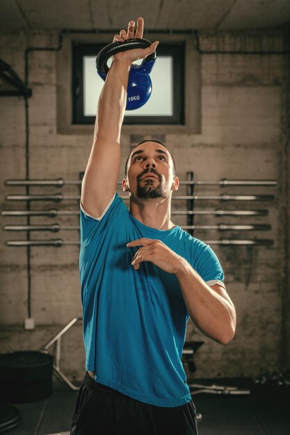 Junger muskulöser Mann bereit, mit Kettlebell im Fitnessstudio zu trainieren.