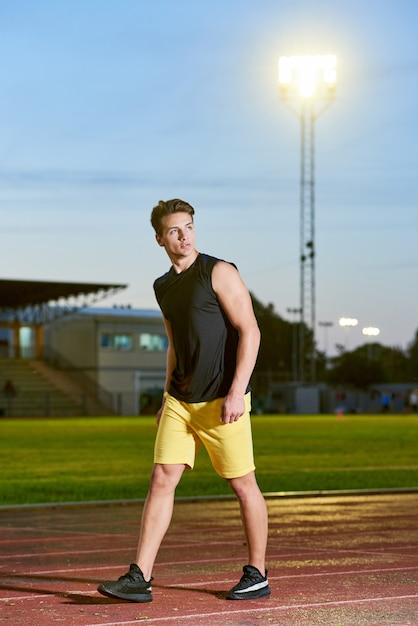 Junger muskulöser Mann, der auf einer Stadionbahn aufwirft