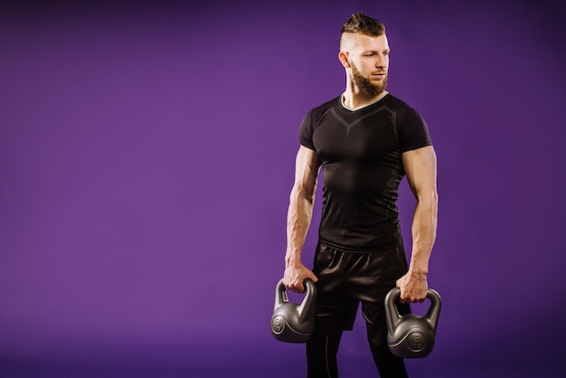 Junger muskulöser Mann, der Übungen mit Gewicht auf lila Studiohintergrund macht. Platz kopieren