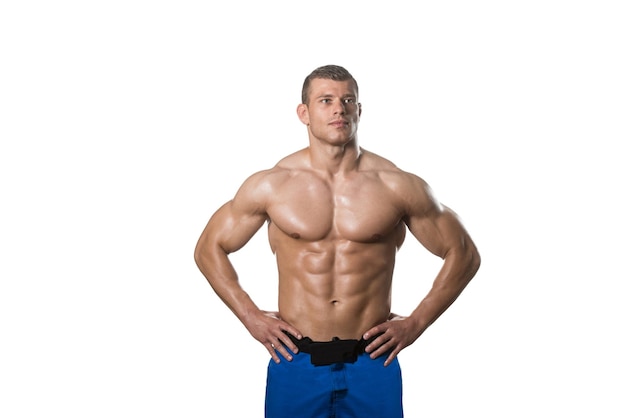 Junger muskulöser Mann, der im Studio aufwirft, das ABS lokalisiert auf weißem Hintergrund zeigt