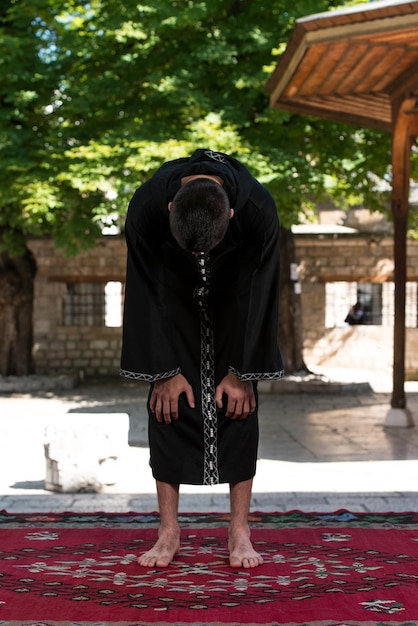 Foto junger muslimischer mann, der traditionelles gebet zu gott macht, während er eine traditionelle kappe dishdasha trägt