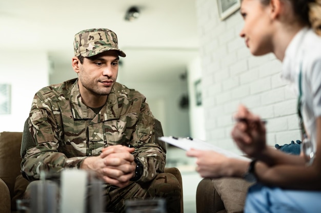 Foto junger nachdenklicher soldat, der sich zu hause mit einer krankenschwester beraten lässt.