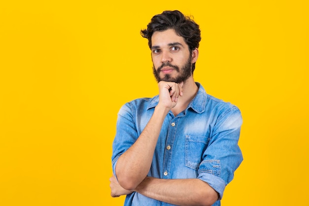 Junger nachdenklicher Studentenjunge auf gelbem Hintergrund Junger Mann, der denkt und eine Idee hat