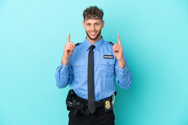 Junger polizeiblonder Mann, isoliert weiß auf blauem Hintergrund, der auf eine großartige Idee zeigt