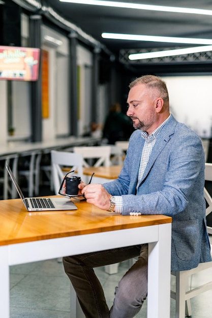 Junger professioneller Geschäftsmann, der im modernen Büro arbeitet. Hübscher erfolgreicher Geschäftsmann im Anzug, der mit Computer arbeitet.