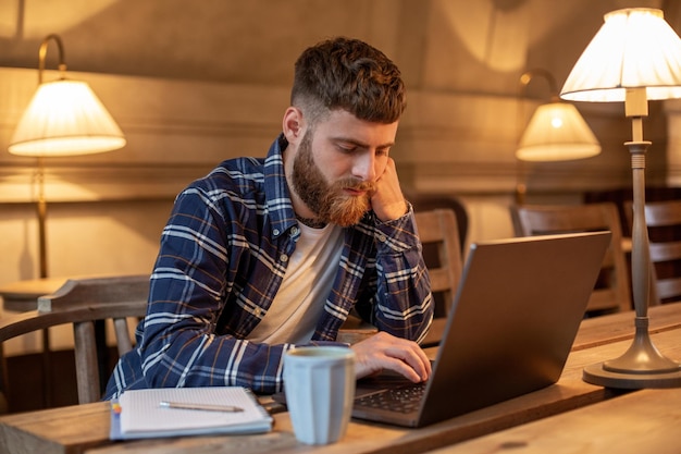 Junger Profi surft auf seinem Laptop in einem Café im Internet