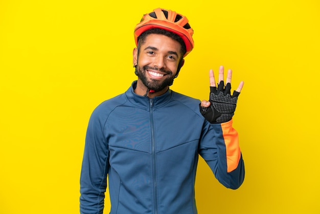 Junger Radfahrer Brasilianer isoliert auf gelbem Hintergrund glücklich und zählt vier mit den Fingern