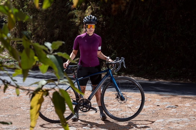 Junger Radfahrer ruht mit seinem Fahrrad am Straßenrand mit Helm und Sonnenbrille