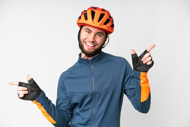 Junger Radfahrer über isoliertem weißem Hintergrund, der mit dem Finger auf die Seitenteile zeigt und glücklich ist