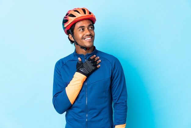 Junger Radfahrermann mit Zöpfen über isolierter Wand, die beim Lächeln nach oben schaut