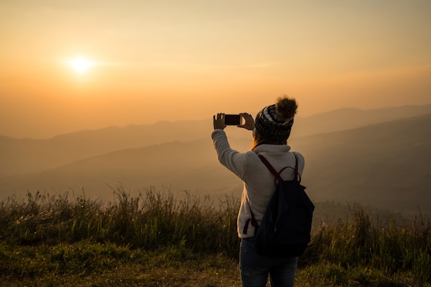 Junger Reisender, der schönen Landschaftssonnenuntergang des Fotos macht