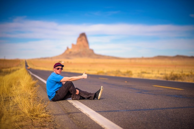 Junger reisender mit einem koffer, der auf einer straße in arizona geht