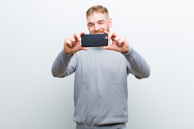 Junger roter Hauptmann mit einem intelligenten Telefon gegen Weiß