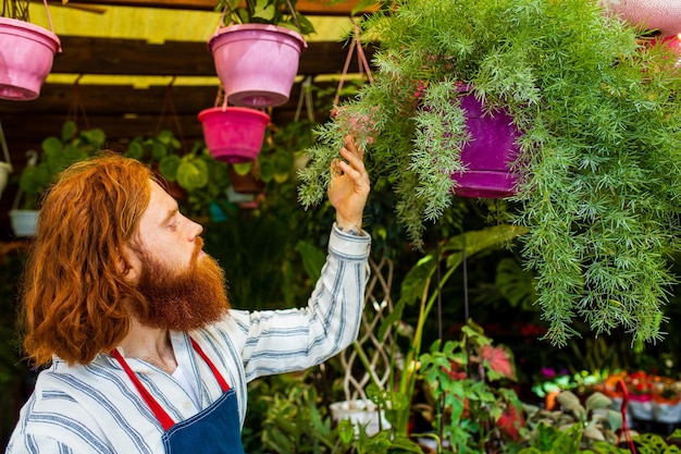 Junger rothaariger, rothaariger Mann mit Schürze, der im Garten oder auf der Plantage arbeitet