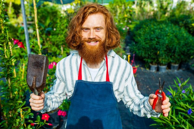 Junger rothaariger, rothaariger Mann mit Schürze, der im Garten oder auf der Plantage arbeitet