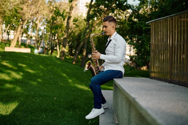 Junger Saxophonist spielt Saxophon im Park