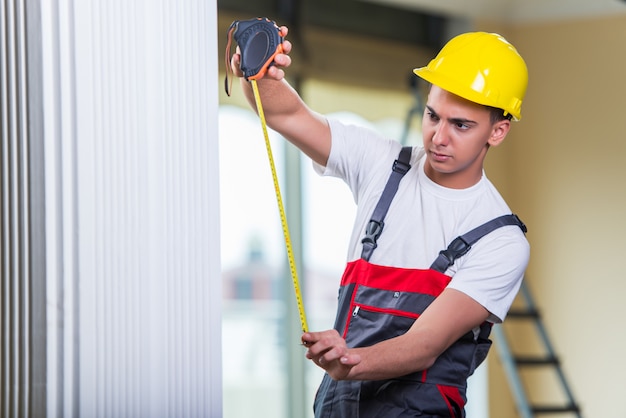 Junger Schlosser mit dem Maßband, das an Reparaturen arbeitet