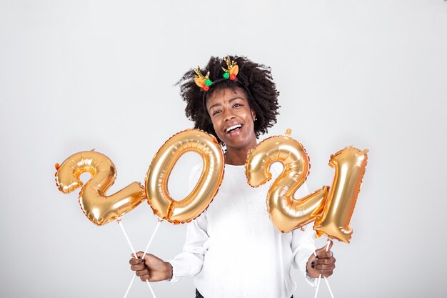 Junger schöner Afrikaner mit Rentierhörnern auf ihrem Kopf, der Luftballons hält