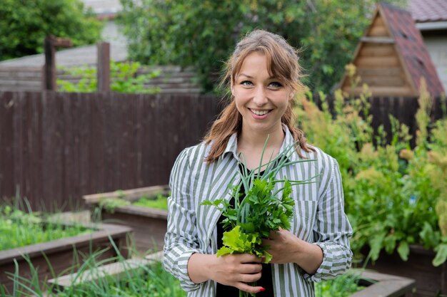 Junger schöner Bauer mit frischen Erntekräutern in den Händen