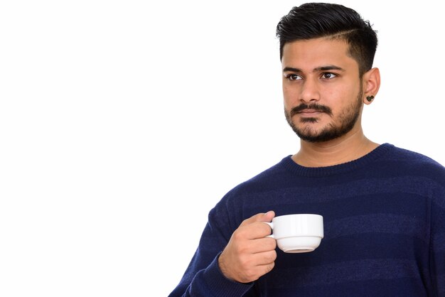 Junger schöner indischer Mann, der Kaffeetasse hält