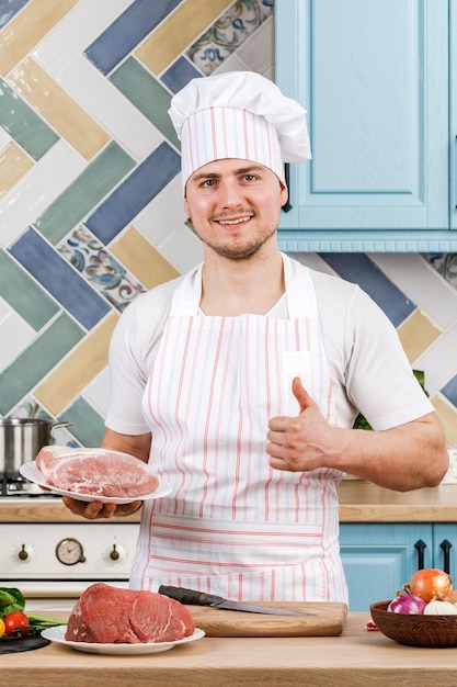 Junger schöner männlicher Koch präsentiert Essen in der Küche
