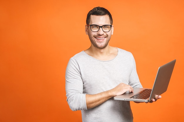 Junger schöner Mann, der Laptop hält und lächelt