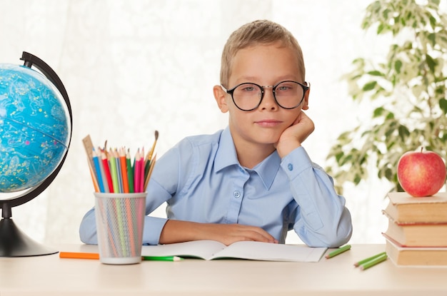 Junger Schüler, der am Tisch sitzt und Hausaufgaben macht