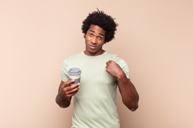 Junger schwarzer Afro-Mann, der arrogant, erfolgreich, positiv und stolz aussieht und auf sich selbst zeigt