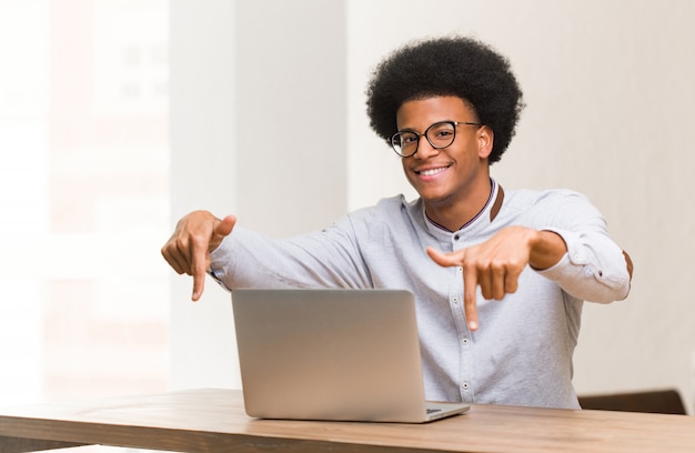 Junger schwarzer mann, der seinen laptop zeigt unterseite mit den fingern verwendet