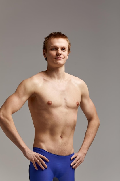 Junger Schwimmer in ausgezeichneter körperlicher Verfassung, auf grauem Hintergrund mit Kopierraum, Aufruf zum Sport, Werbebanner