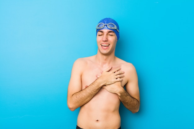 Junger Schwimmermann, der Hände auf Herzen, Konzept des Glückes halten lacht.