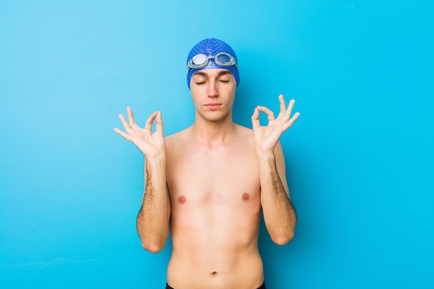 Junger Schwimmermann entspannt sich nach hartem Arbeitstag, sie führt Yoga durch.