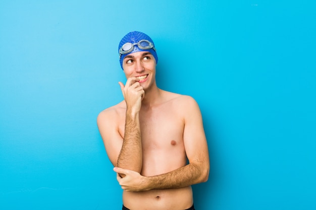 Junger Schwimmermann entspannte sich das Denken an etwas, das einen Kopienraum betrachtet.