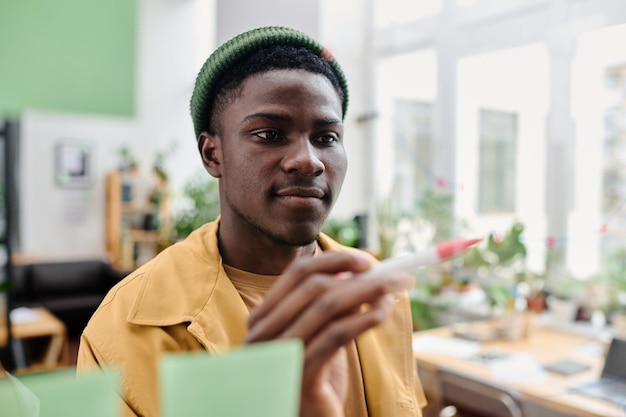 Junger selbstbewusster schwarzer Mann in Freizeitkleidung, der auf eine transparente Anschlagtafel zeigt