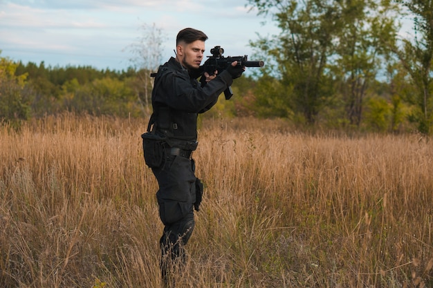 Junger Soldat in schwarzer Uniform, der ein Sturmgewehr zielt