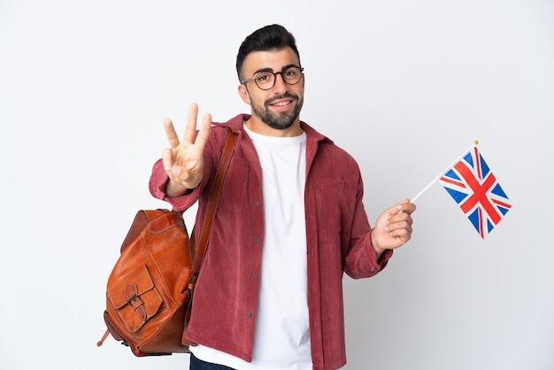 Junger spanischer Mann, der eine britische Flagge glücklich hält und drei mit den Fingern zählt