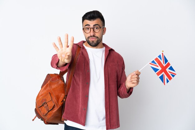 Junger spanischer Mann, der eine britische Flagge glücklich hält und vier mit den Fingern zählt