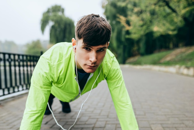 Junger Sportler, der Liegestütze macht Fitness-Mann, der morgens im Park Trainingsübungen macht Menschen- und Sportkonzept