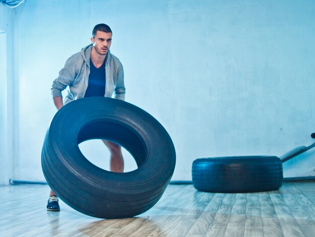 Junger Sportler hebt ein großes Gewichtsrad an. Trainingsprozess. Funktionstraining