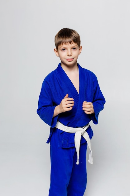 Junger Sportler im blauen Kimono für Sambo-Judo posiert auf weißem Hintergrund und sieht gerade aus