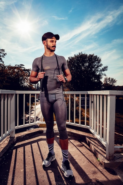 Junger Sportler ruht sich nach dem Training an der Brücke aus und schaut weg.