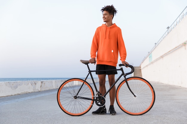 Junger Sportmann draußen am Strand mit Fahrrad