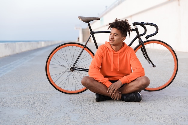 Junger Sportmann draußen am Strand mit Fahrrad