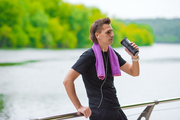 Junger Sportmann mit Tuch und Flasche Wasser, nachdem draußen gerüttelt worden ist