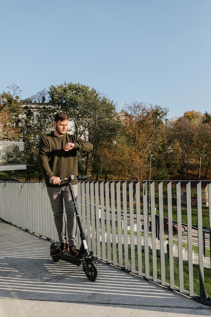 Junger starker Mann, der mit elektrischem Tretroller fährt